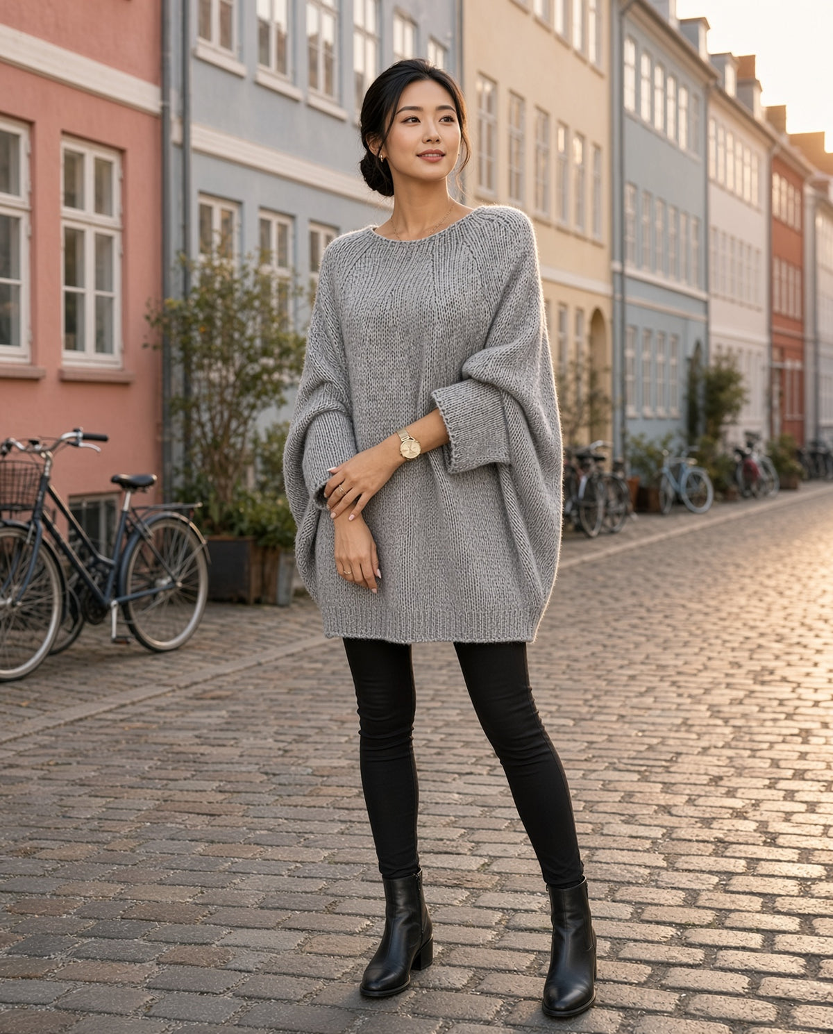 Model wearing the Cozy Batwing Shawl Sweater in Gray on a Copenhagen cobblestone street