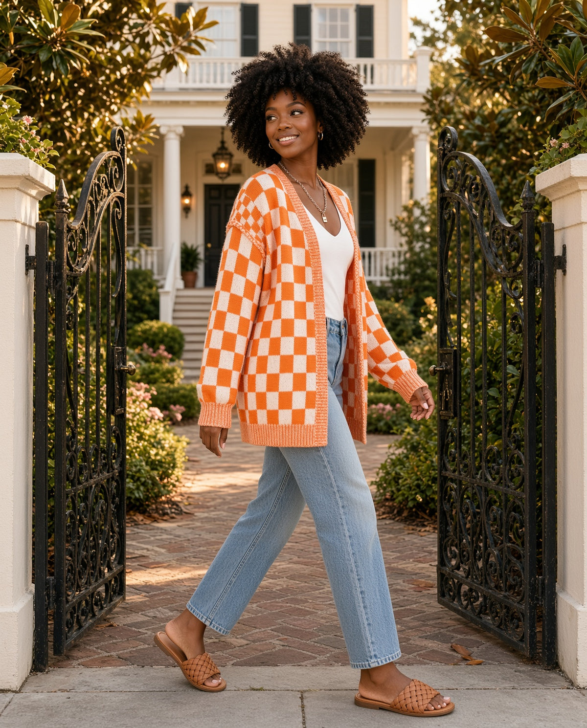 Model wearing the Checkered Pattern Open Front Cardigan in Tangerine at a Charleston garden gate